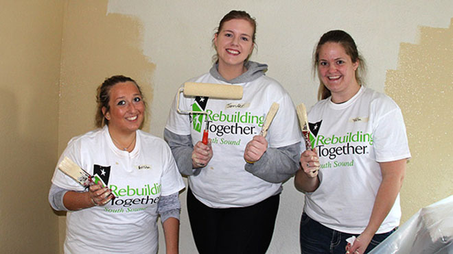 Three women holding paint rollers