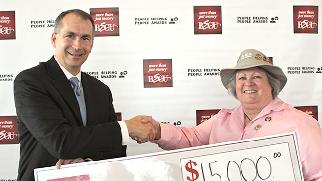 a man and woman shaking hands while holding a large check