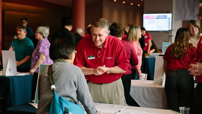 a man in red shirt listing to a woman talk
