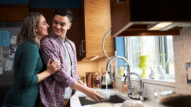 a man and woman standing at a kitchen sink