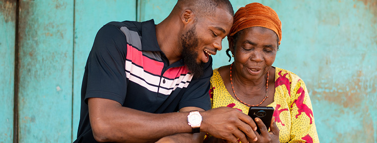 Young man helping older woman use phone