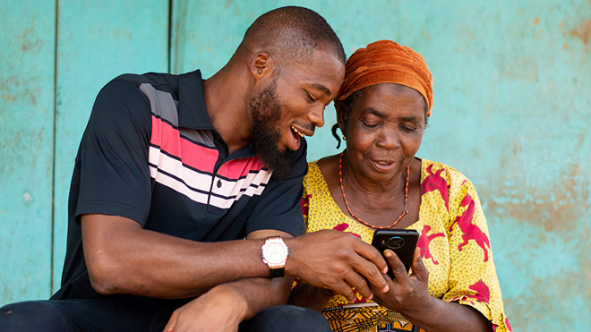Young man helping older woman use phone