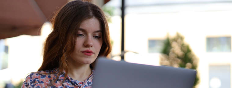 Young person sitting outside looking at laptop