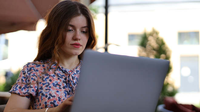 Young person sitting outside looking at laptop