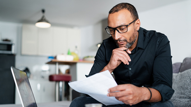 A man wearing glasses looking at paperwork